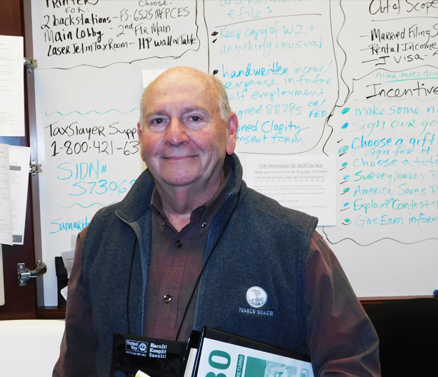 An older man holding binders and smiling